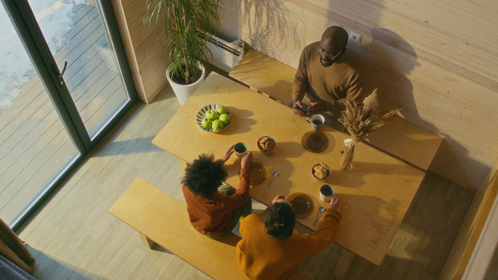 A family sharing breakfast at a wooden table in morning light